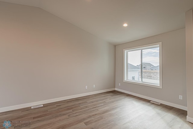 spare room with light hardwood / wood-style flooring and lofted ceiling