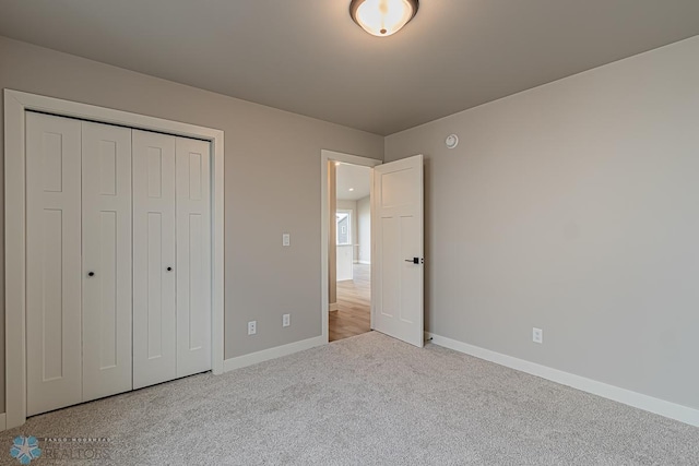 unfurnished bedroom with light colored carpet and a closet