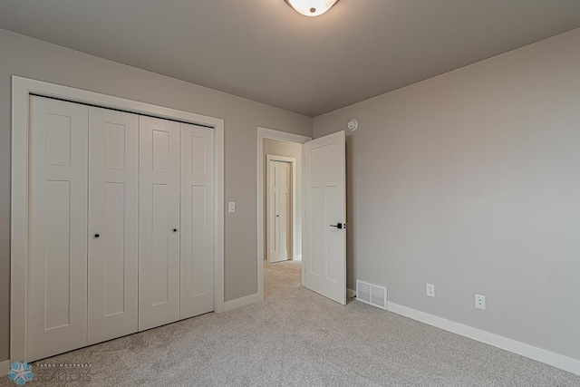 unfurnished bedroom featuring light carpet and a closet