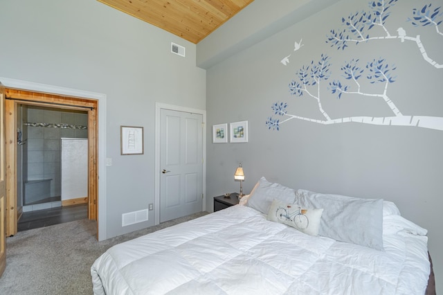 carpeted bedroom featuring visible vents, ensuite bathroom, wooden ceiling, and a towering ceiling