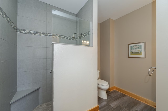 bathroom with baseboards, toilet, walk in shower, and wood finished floors