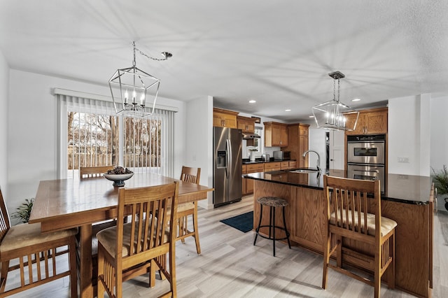 dining room with light wood-type flooring, sink, and a notable chandelier