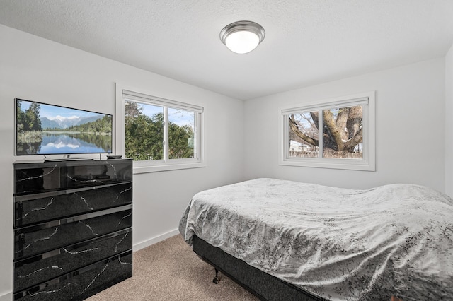 bedroom with light colored carpet and a textured ceiling