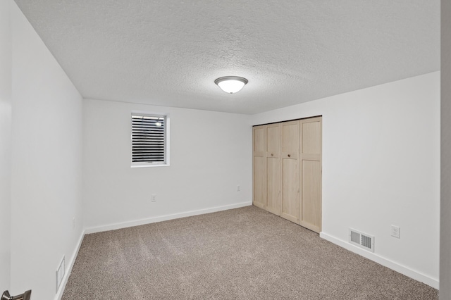 unfurnished bedroom with a closet, a textured ceiling, and carpet flooring