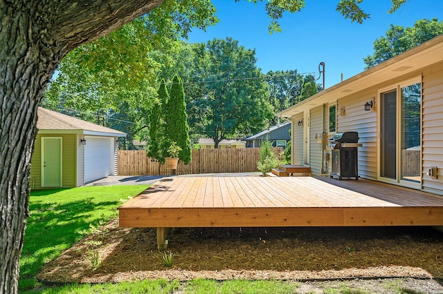 deck featuring a garage, an outdoor structure, a yard, and grilling area