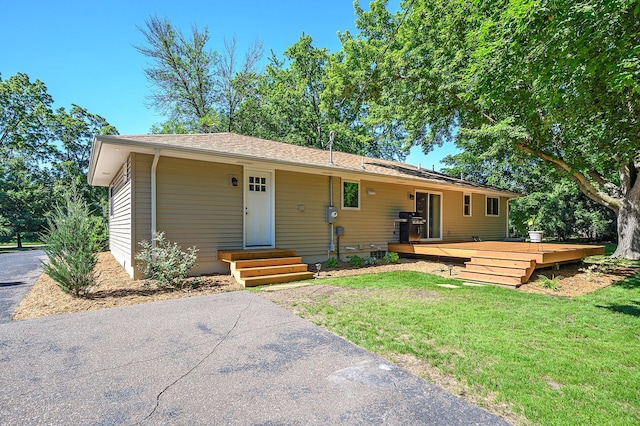 ranch-style home featuring a wooden deck and a front yard