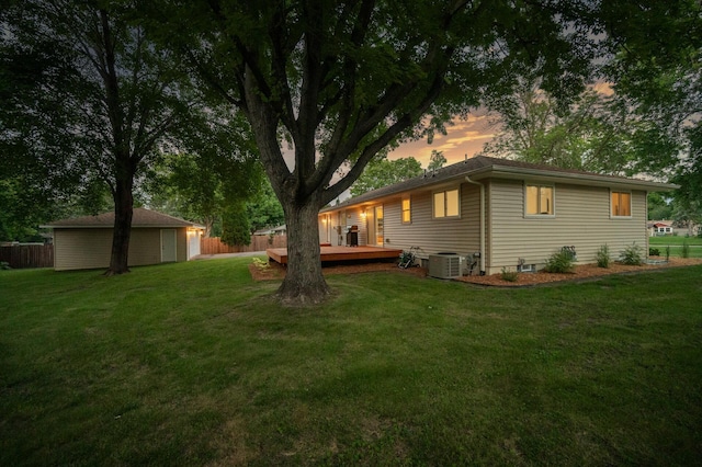 yard at dusk featuring a wooden deck, central AC unit, and a storage unit