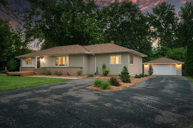 ranch-style house featuring an outbuilding, a garage, and a lawn