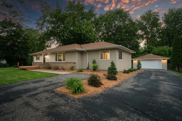 ranch-style house with a garage, an outdoor structure, and a lawn