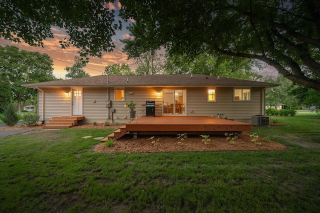 back house at dusk with central AC, a deck, and a lawn