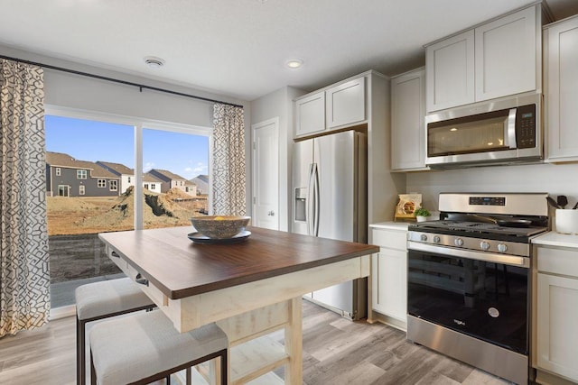 kitchen featuring light wood-type flooring, stainless steel appliances, and wooden counters