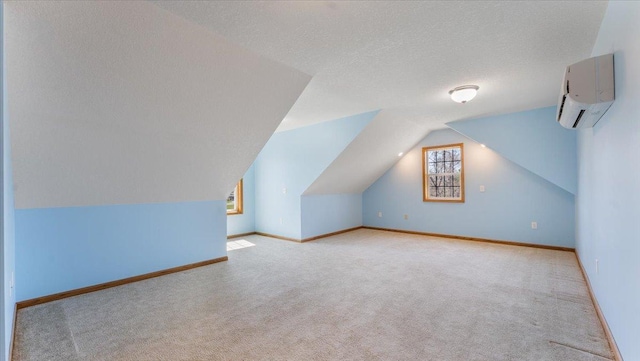 24455 Crocus St NW, Saint Francis, MN 55070 - additional living space featuring carpet floors, lofted ceiling, baseboards, a textured ceiling, and a wall mounted AC