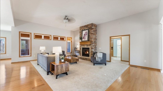 24455 Crocus St NW, Saint Francis, MN 55070 - living room featuring a ceiling fan, visible vents, a fireplace, baseboards, and light wood finished floors