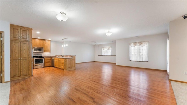 24455 Crocus St NW, Saint Francis, MN 55070 - kitchen featuring a peninsula, brown cabinets, a sink, light wood-style flooring, and stainless steel appliances