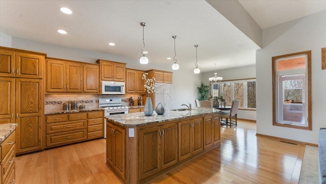 24455 Crocus St NW, Saint Francis, MN 55070 - kitchen with brown cabinetry, decorative backsplash, white appliances, light wood-style floors, and stone countertops