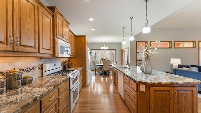 24455 Crocus St NW, Saint Francis, MN 55070 - kitchen with light wood-style floors, brown cabinetry, white appliances, and a chandelier