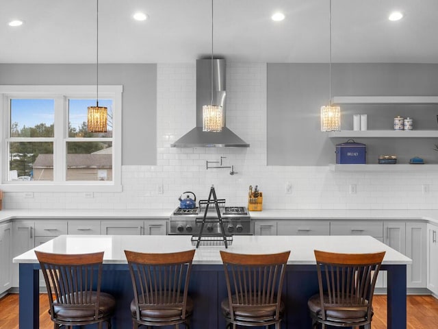 kitchen with decorative backsplash, a kitchen breakfast bar, and wall chimney range hood