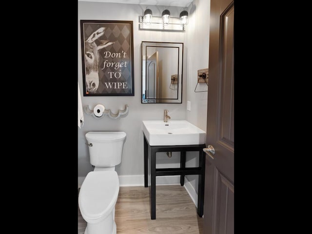 bathroom with toilet, wood-type flooring, and sink