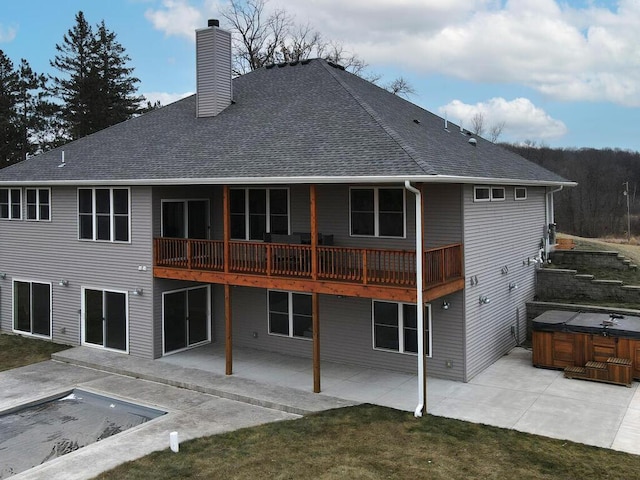 rear view of house with a patio, a lawn, and a pool with hot tub