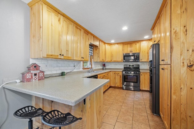 kitchen with a kitchen breakfast bar, sink, light brown cabinetry, kitchen peninsula, and stainless steel appliances