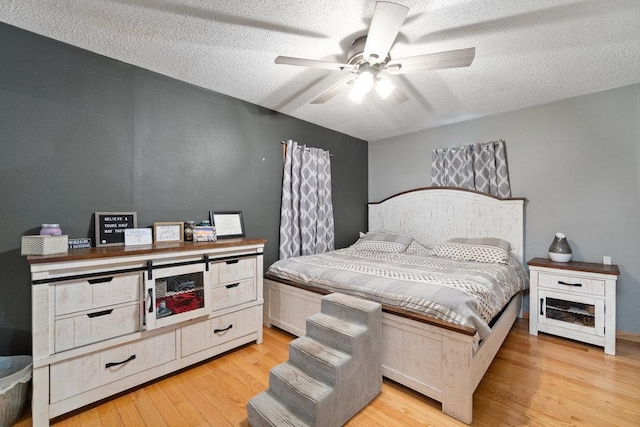 bedroom with ceiling fan, a textured ceiling, and light hardwood / wood-style flooring