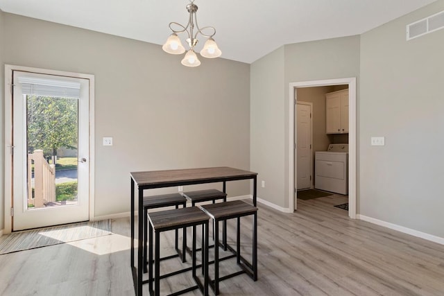 dining space with a chandelier, washer / dryer, and light hardwood / wood-style floors