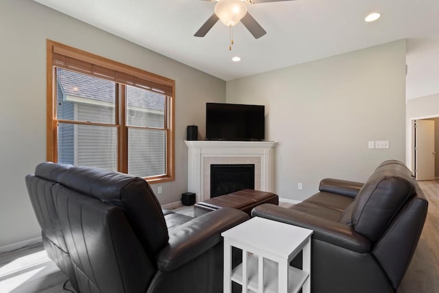 living room with ceiling fan and a tiled fireplace