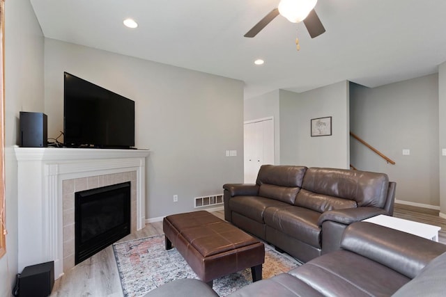 living room featuring ceiling fan, a fireplace, and light hardwood / wood-style flooring