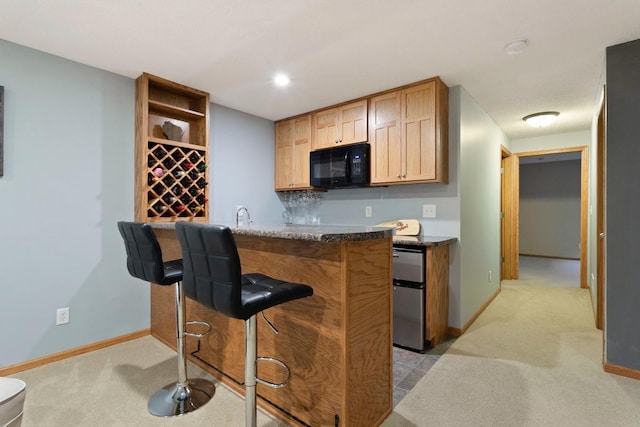 kitchen with a breakfast bar, sink, kitchen peninsula, and light carpet