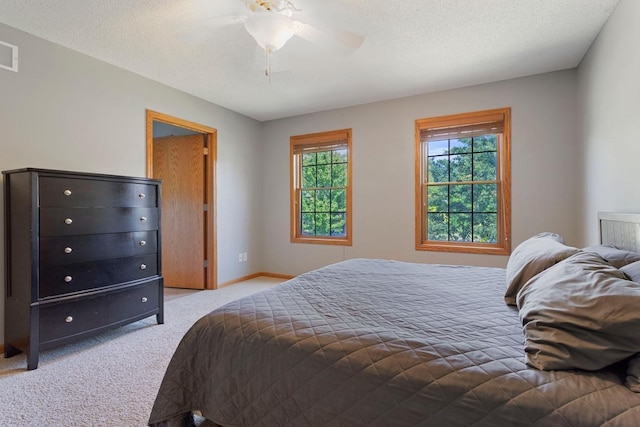 bedroom featuring a textured ceiling, light colored carpet, and ceiling fan