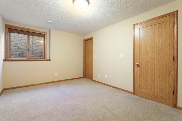 empty room with light carpet and a textured ceiling