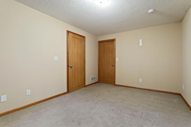 carpeted empty room featuring a textured ceiling