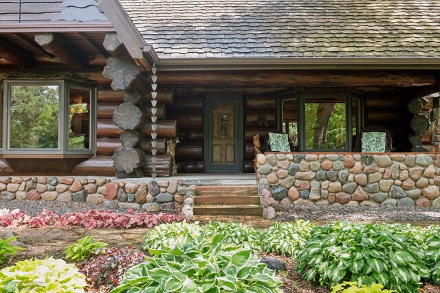 entrance to property with log siding and a porch