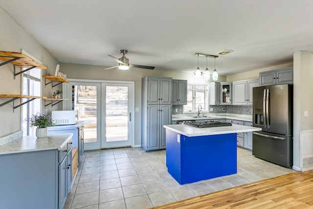 kitchen featuring a center island, sink, ceiling fan, decorative backsplash, and appliances with stainless steel finishes