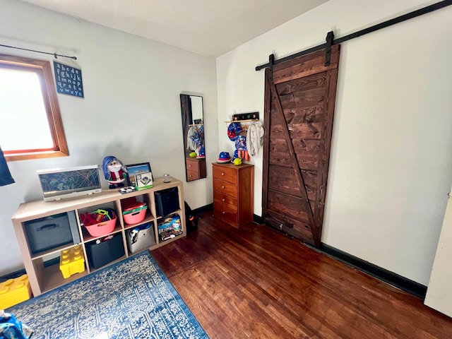 game room with a barn door and dark hardwood / wood-style floors