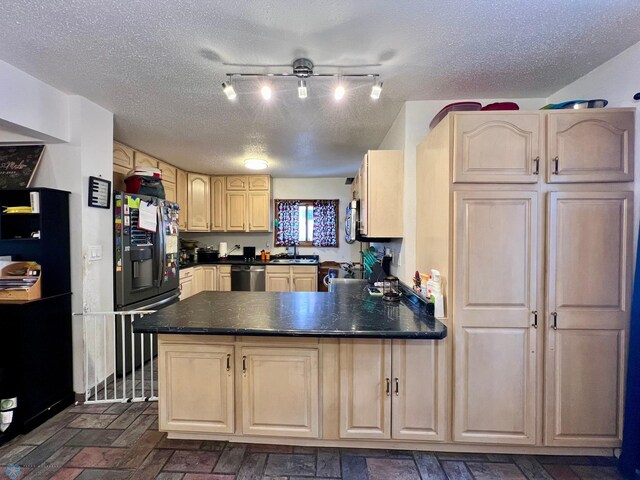 kitchen featuring stainless steel appliances, kitchen peninsula, a textured ceiling, and light brown cabinets