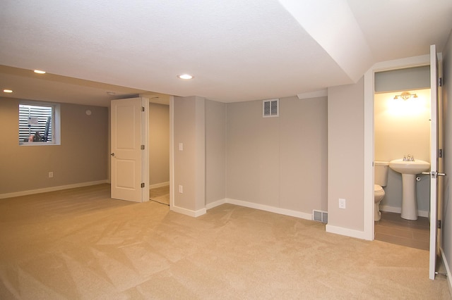 basement with light colored carpet and sink