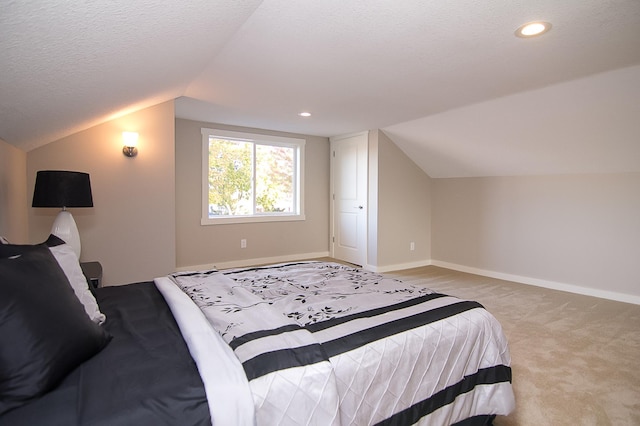 bedroom featuring a textured ceiling, light colored carpet, and lofted ceiling