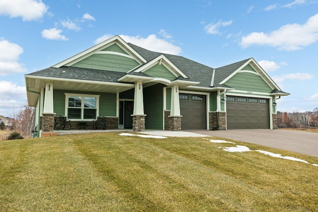 craftsman inspired home featuring a porch, a garage, and a front lawn