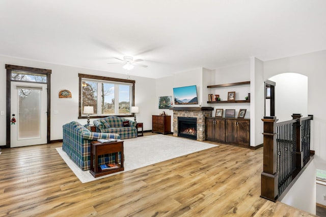 living room featuring ceiling fan, a fireplace, and light wood-type flooring