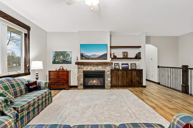 living room with ceiling fan, light wood-type flooring, and a fireplace