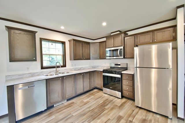 kitchen featuring light wood-type flooring, dark brown cabinetry, stainless steel appliances, crown molding, and sink