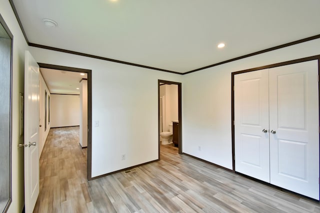 unfurnished bedroom featuring light wood-type flooring, a closet, crown molding, and connected bathroom