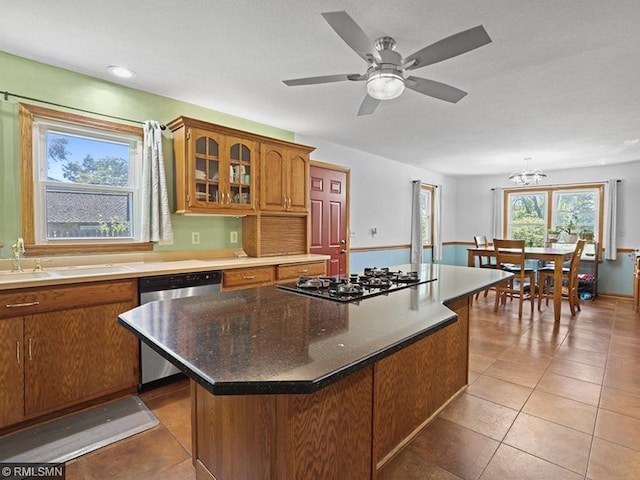 kitchen with light tile patterned flooring, ceiling fan with notable chandelier, sink, appliances with stainless steel finishes, and a kitchen island