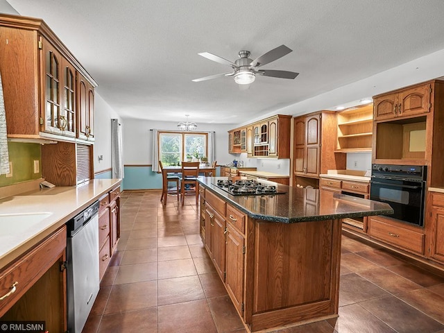 kitchen with dark tile patterned floors, a kitchen island, ceiling fan with notable chandelier, and appliances with stainless steel finishes