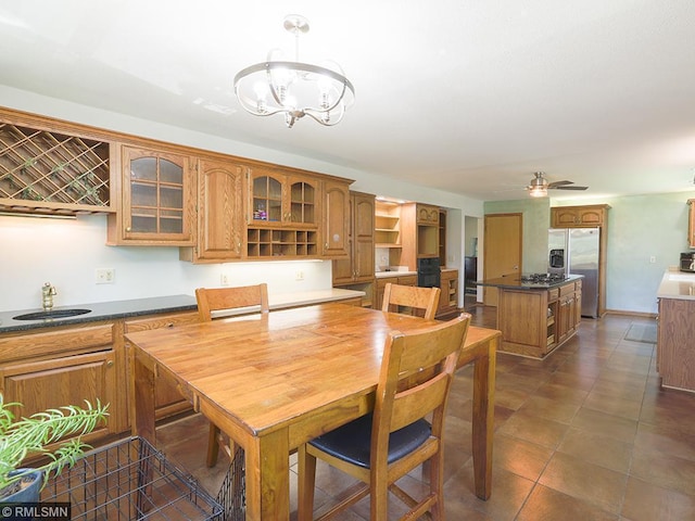 tiled dining room featuring ceiling fan with notable chandelier and sink