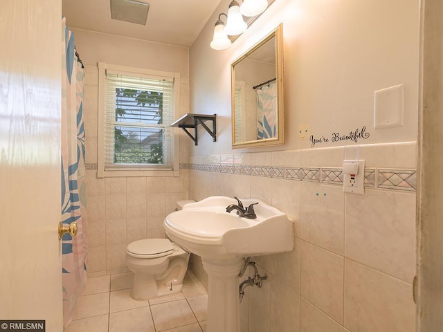 bathroom with tile patterned flooring, sink, toilet, and tile walls