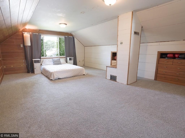 unfurnished bedroom featuring wood walls, carpet floors, and vaulted ceiling