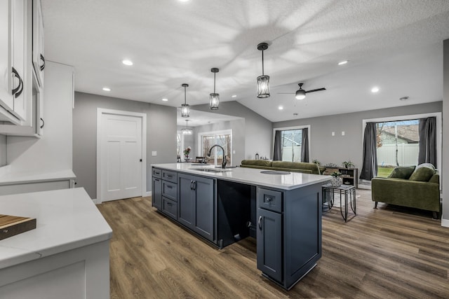 kitchen featuring a center island with sink, white cabinets, hanging light fixtures, ceiling fan, and a textured ceiling