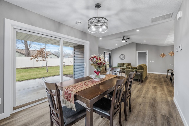 dining space featuring hardwood / wood-style floors, ceiling fan with notable chandelier, plenty of natural light, and lofted ceiling